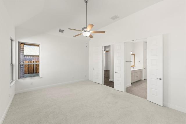 unfurnished bedroom with lofted ceiling, sink, ensuite bath, ceiling fan, and light carpet