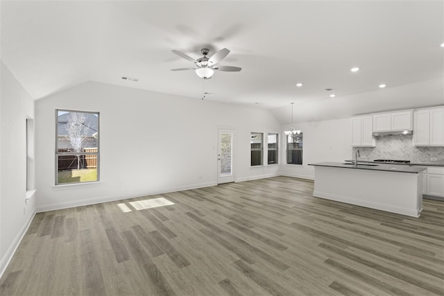 unfurnished living room featuring a wealth of natural light, sink, ceiling fan with notable chandelier, and lofted ceiling