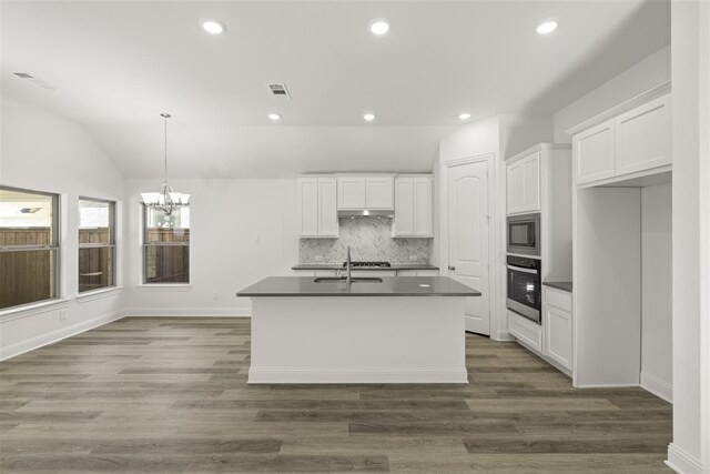 kitchen with a center island with sink, stainless steel oven, white cabinetry, and vaulted ceiling