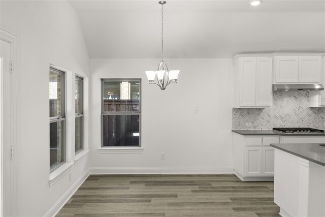 kitchen with pendant lighting, lofted ceiling, dark wood-type flooring, white cabinets, and stainless steel gas cooktop