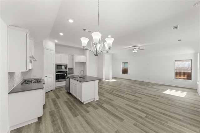 kitchen featuring a center island with sink, ceiling fan with notable chandelier, sink, appliances with stainless steel finishes, and white cabinetry