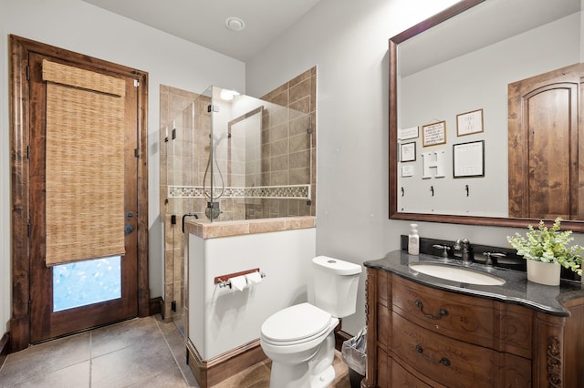 bathroom with vanity, toilet, tiled shower, and tile patterned floors