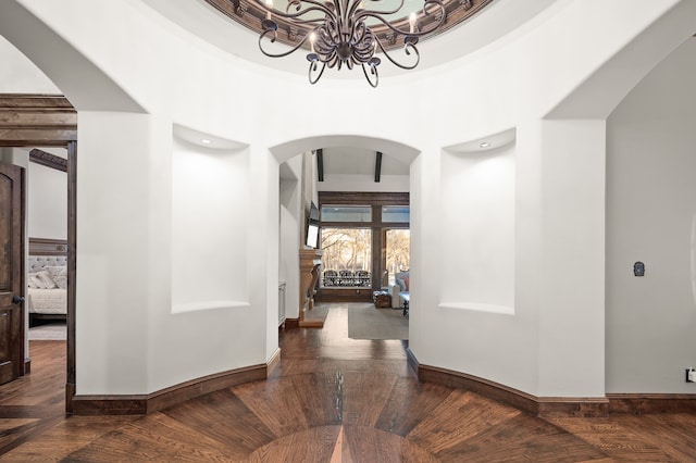 corridor with dark wood-type flooring and an inviting chandelier