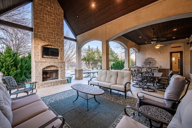 view of patio / terrace featuring ceiling fan and an outdoor living space with a fireplace