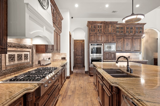 kitchen featuring appliances with stainless steel finishes, tasteful backsplash, wood-type flooring, and sink