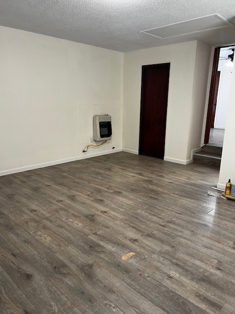 unfurnished room featuring dark hardwood / wood-style flooring, heating unit, and a textured ceiling