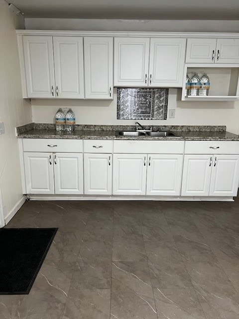 kitchen featuring dark stone countertops, sink, and white cabinetry