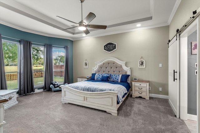 carpeted bedroom featuring a barn door, a tray ceiling, ceiling fan, and crown molding