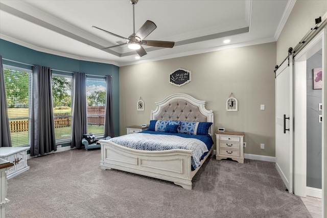 carpeted bedroom featuring baseboards, a barn door, a tray ceiling, and crown molding