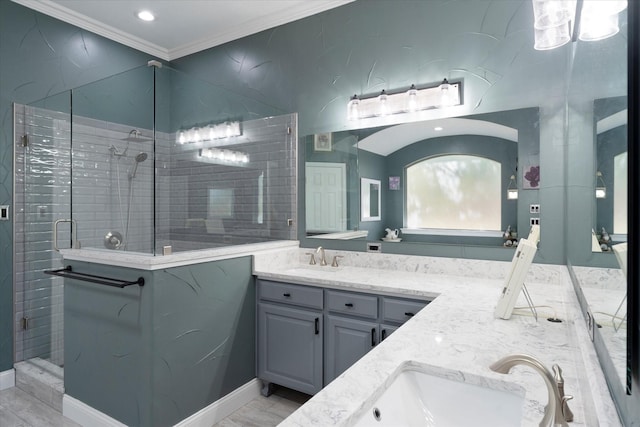 bathroom featuring double vanity, a shower stall, ornamental molding, and a sink