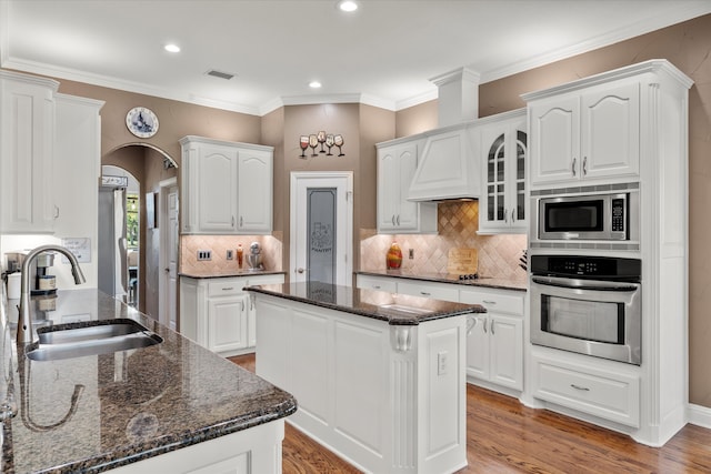 kitchen with a kitchen island, wood-type flooring, appliances with stainless steel finishes, sink, and white cabinetry