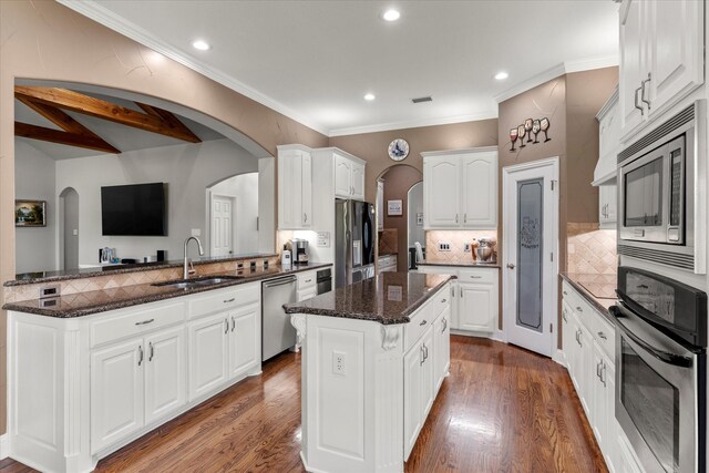 kitchen with a kitchen island, dark hardwood / wood-style flooring, stainless steel appliances, sink, and white cabinets