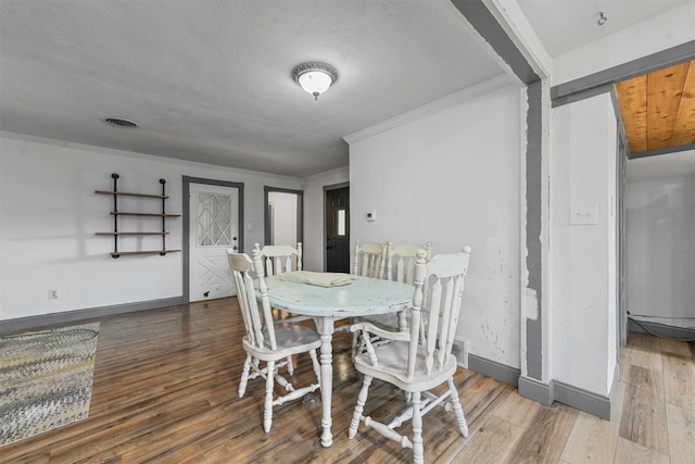 dining space featuring hardwood / wood-style flooring, ornamental molding, and a textured ceiling