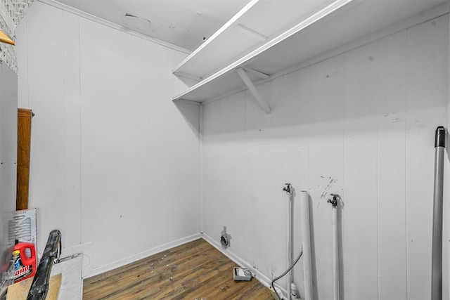 clothes washing area featuring wood walls and dark wood-type flooring