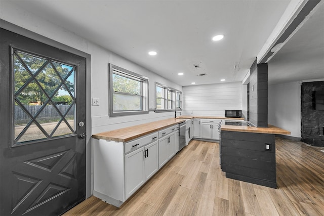 kitchen featuring light wood-type flooring, dishwasher, white cabinetry, and wood counters