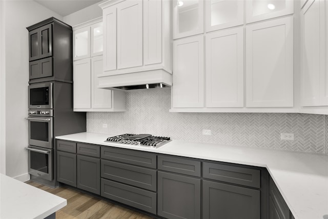 kitchen with white cabinets, dark hardwood / wood-style flooring, stainless steel appliances, and backsplash