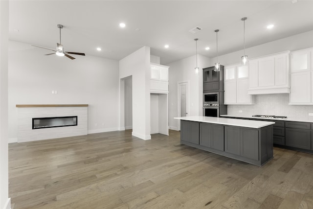 kitchen featuring appliances with stainless steel finishes, light wood-type flooring, gray cabinetry, white cabinets, and a center island