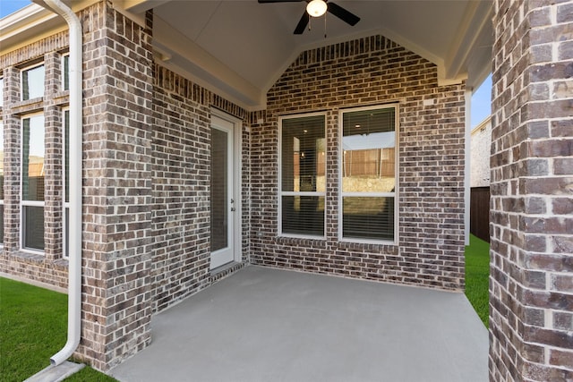 view of exterior entry featuring ceiling fan and a patio