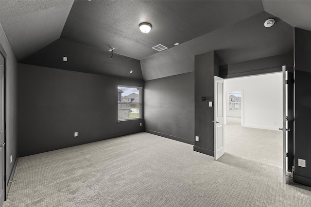 carpeted spare room featuring lofted ceiling and a textured ceiling