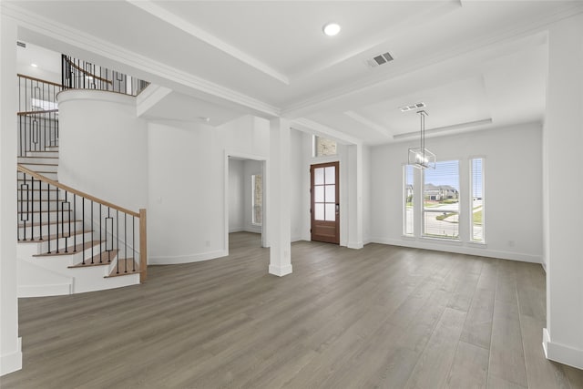 unfurnished living room featuring a tray ceiling, hardwood / wood-style floors, and an inviting chandelier