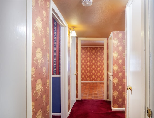 corridor with a textured ceiling and carpet flooring