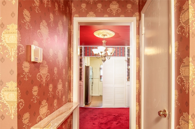 hall with an inviting chandelier and carpet