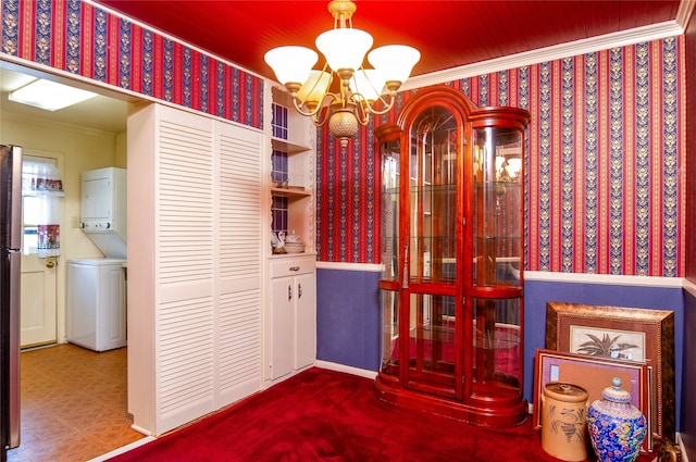 wine room featuring crown molding, a chandelier, and stacked washer / drying machine