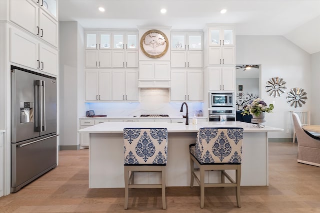 kitchen featuring light hardwood / wood-style flooring, white cabinetry, stainless steel appliances, and an island with sink