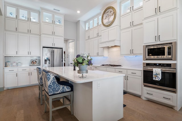 kitchen featuring appliances with stainless steel finishes, a center island, light hardwood / wood-style flooring, and white cabinetry