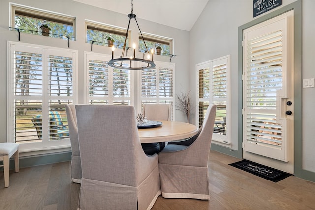 dining area featuring hardwood / wood-style floors, lofted ceiling, a healthy amount of sunlight, and a notable chandelier