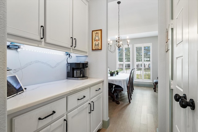 kitchen with a chandelier, white cabinets, light hardwood / wood-style floors, and decorative light fixtures