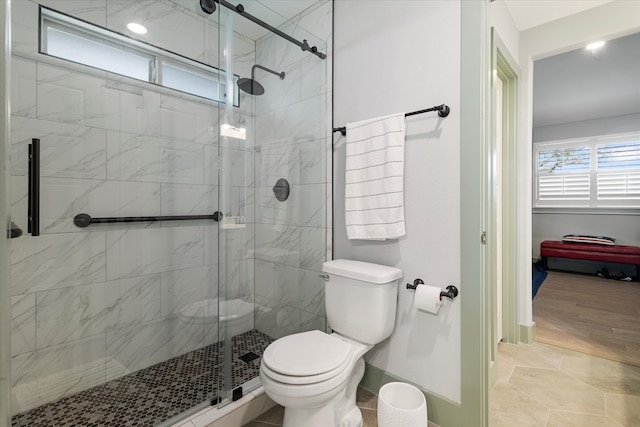 bathroom featuring hardwood / wood-style flooring, toilet, and a shower with door