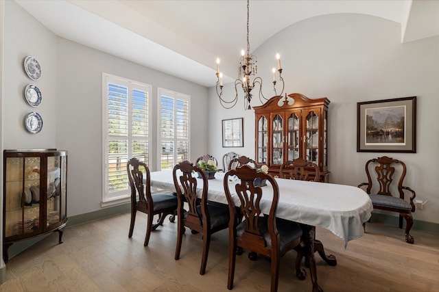 dining space featuring lofted ceiling, a notable chandelier, and light wood-type flooring