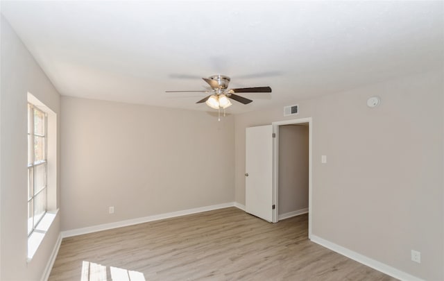 empty room featuring a healthy amount of sunlight, ceiling fan, and light hardwood / wood-style flooring