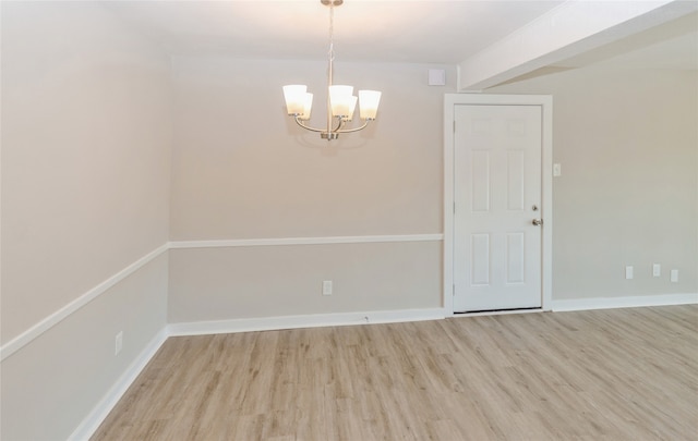 unfurnished room with a notable chandelier and light hardwood / wood-style floors