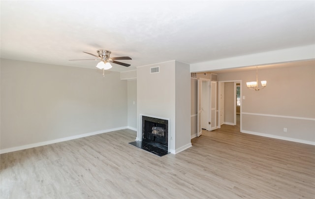 unfurnished living room featuring a high end fireplace, light wood-type flooring, and ceiling fan with notable chandelier