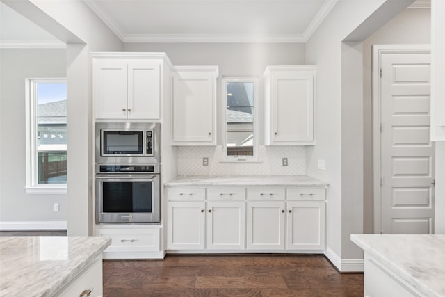 kitchen with appliances with stainless steel finishes, white cabinets, backsplash, and dark wood-type flooring