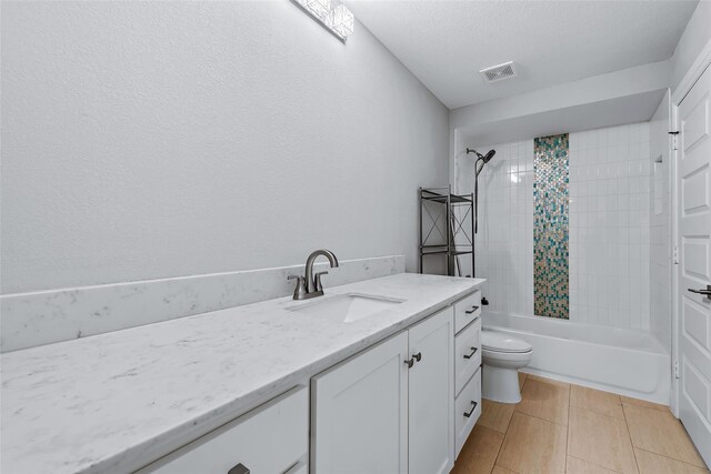 full bathroom with vanity, a textured ceiling, tile patterned flooring, toilet, and tiled shower / bath