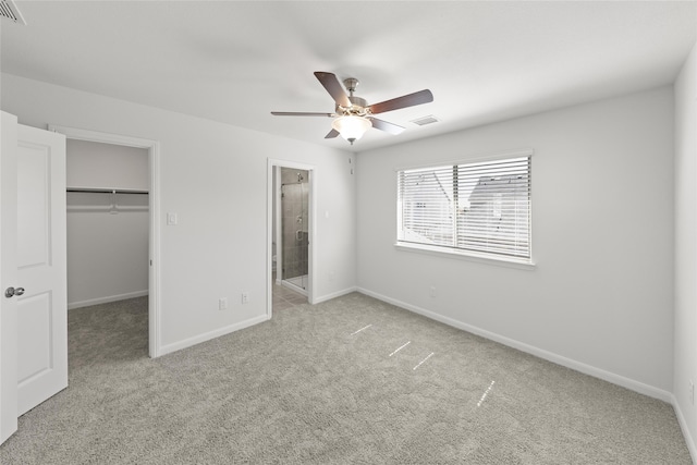 unfurnished bedroom with ceiling fan, a closet, a spacious closet, and light colored carpet