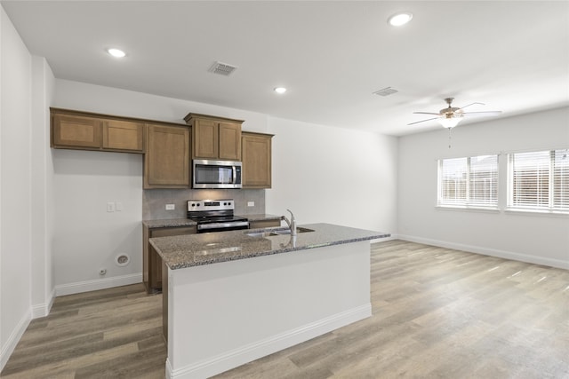 kitchen featuring a center island with sink, light hardwood / wood-style flooring, sink, ceiling fan, and appliances with stainless steel finishes