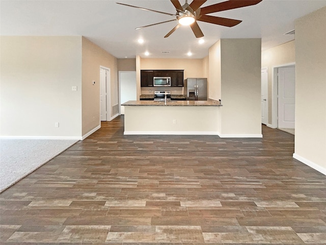 kitchen featuring stainless steel appliances, open floor plan, baseboards, and wood finished floors