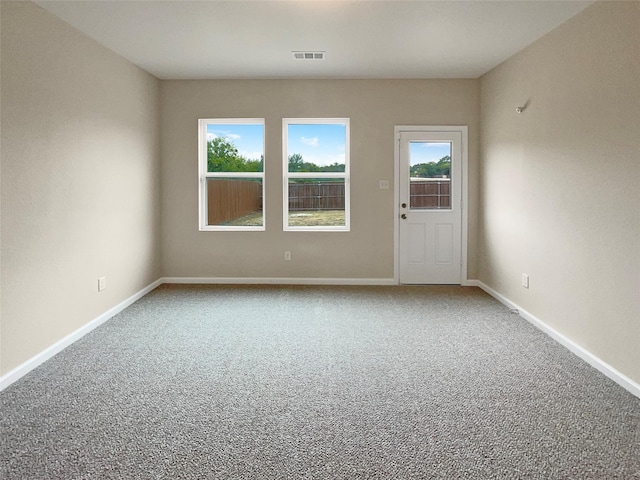 empty room featuring carpet flooring, visible vents, and baseboards