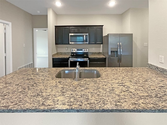 kitchen with sink, stainless steel appliances, and light stone countertops