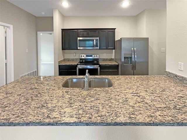 kitchen with visible vents, light stone counters, stainless steel appliances, a sink, and recessed lighting