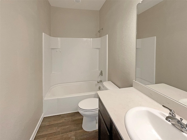 bathroom featuring toilet, wood finished floors, vanity, baseboards, and shower / washtub combination