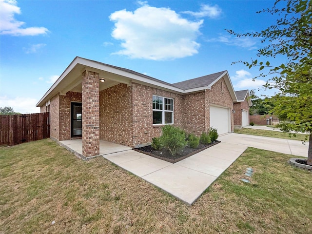 view of front of house featuring fence, a front lawn, concrete driveway, and brick siding