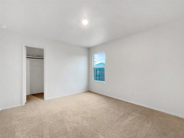 unfurnished bedroom featuring a closet, light carpet, and baseboards