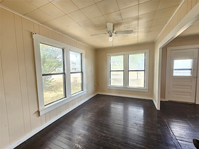 empty room featuring dark wood-type flooring, ceiling fan, and a wealth of natural light