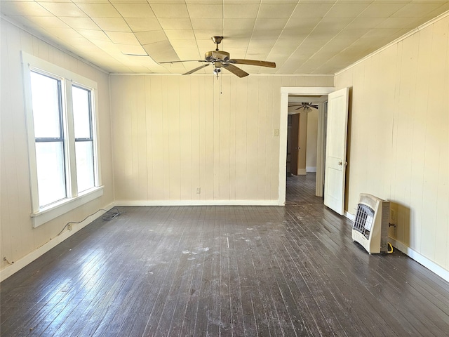 unfurnished room featuring plenty of natural light, ceiling fan, dark hardwood / wood-style flooring, and heating unit