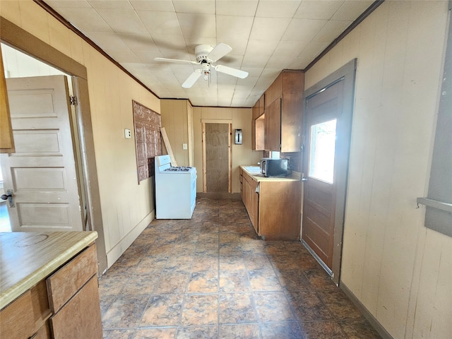 kitchen with washer / clothes dryer, ceiling fan, and wooden walls